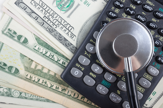 Financial analysis, audit or accounting - Stethoscope over a calculator and dollar bills. Medical costs, financial concept.